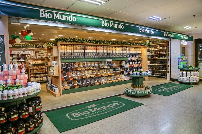 Fachada interna de loja Bio Mundo com prateleiras de produtos naturais, suplementos e alimentos saudáveis organizados.